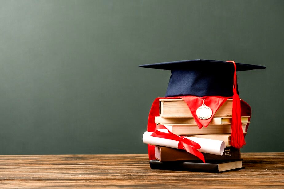 books, academic cap, medal and diploma on wooden surface isolated on grey