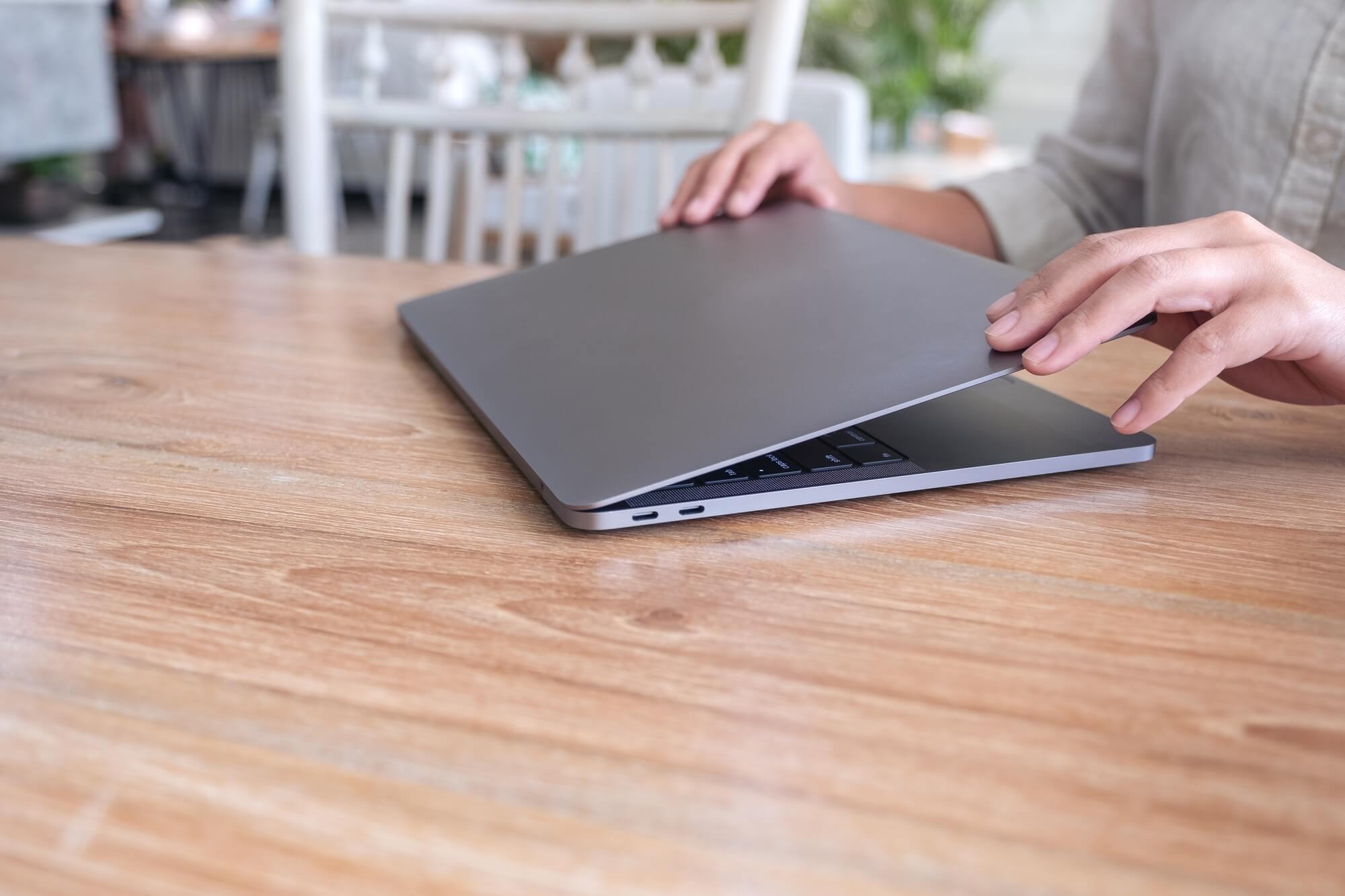 Closeup image of hands close and open a laptop computer on table after finished using it