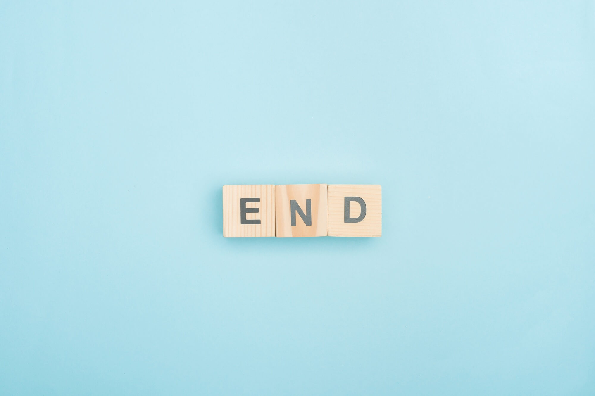 top view of end lettering made of wooden cubes on blue background